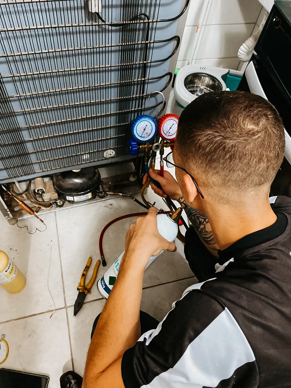 Técnico da Prime fazendo recarga de gás em uma geladeira com manômetro